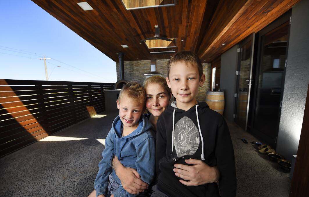 OVERWHELMED: Belinda Scott sits with her sons Archie, 5 and Harvey,8, on the family's dream outdoor dining area which was built by the community.  Picture: Luka Kauzlaric 