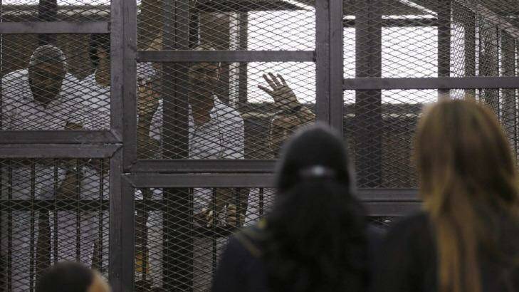 Al Jazeera journalists Mohammed Fahmy, Peter Greste and Baher Mohamed wave to family and friends during their trial in Cairo.   Photo: Asmaa Waguih