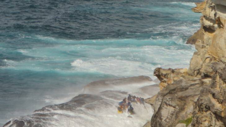 A wave sweeps over rescuers on the rock shelf at North Curl Curl. Photo: Susannah Williams
