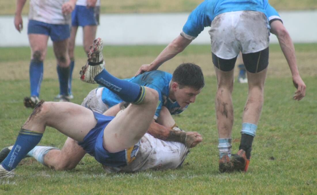 Queanbeyan Blue Levi Freeman comes up with a big hit on a Goulburn Workers Bulldogs player in muddy conditions at Seiffert Oval on Saturday. Photo: Joshua Matic.