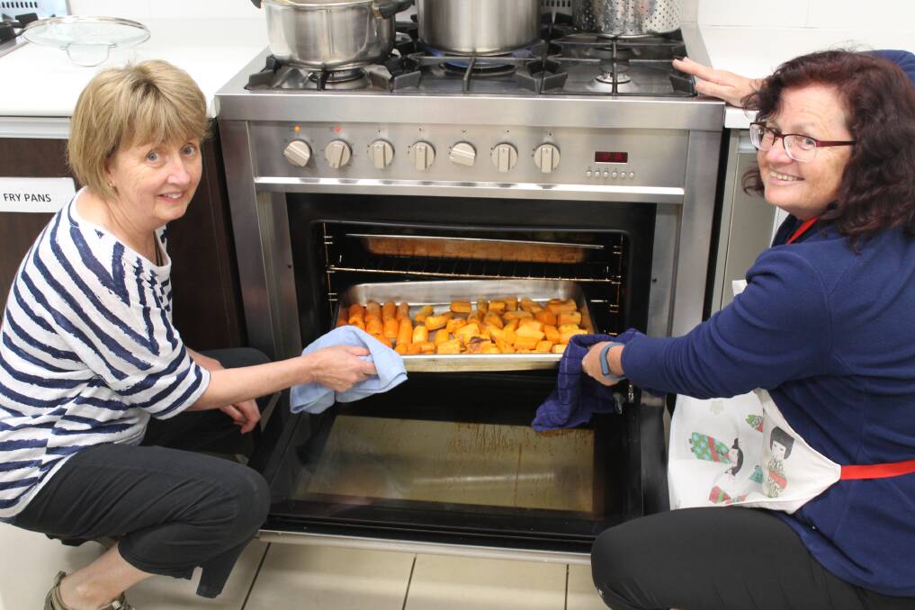 Volunteers Jeanette Buckley (left) and Kris Mitchell helping out in the kitchen at St Benedict's Community Centre. Photo: Miles Thompson