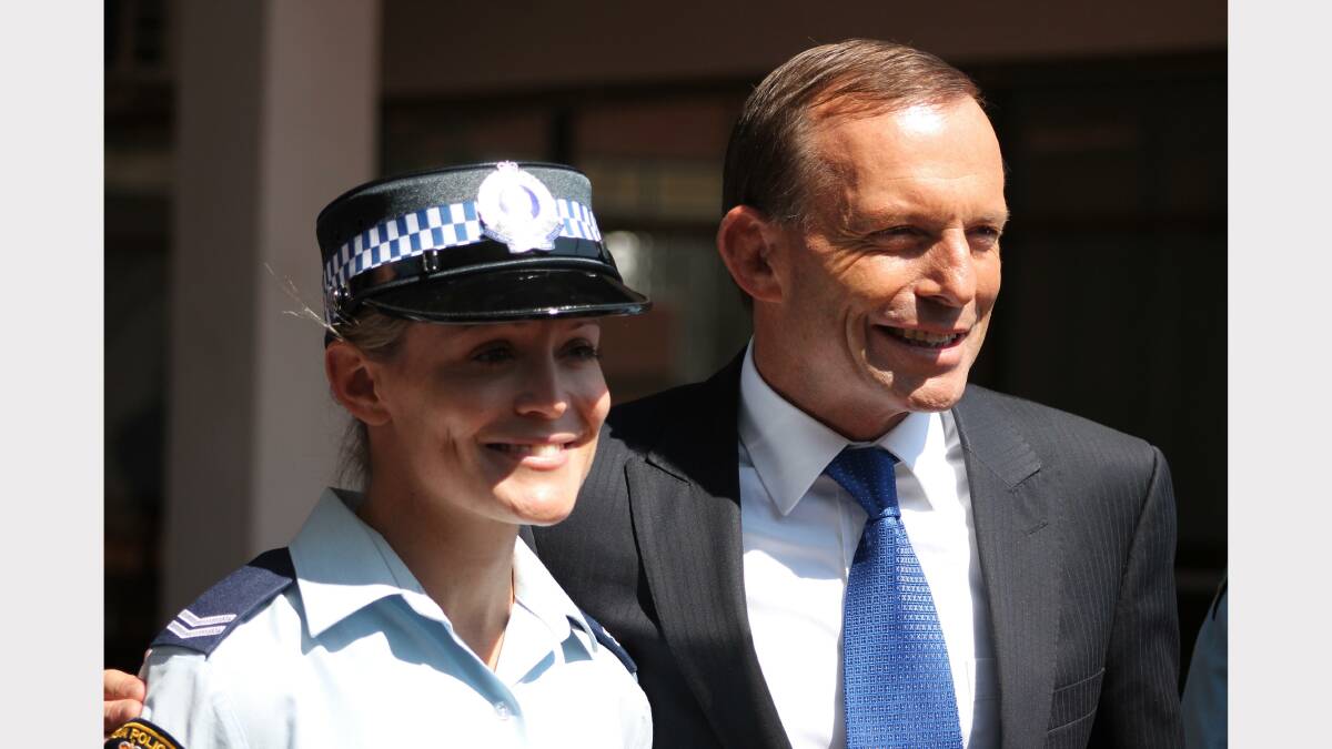 Tony Abbott and Queanbeyan police officer Alexa McKay pose for the cameras. Photo: Andrew Johnston