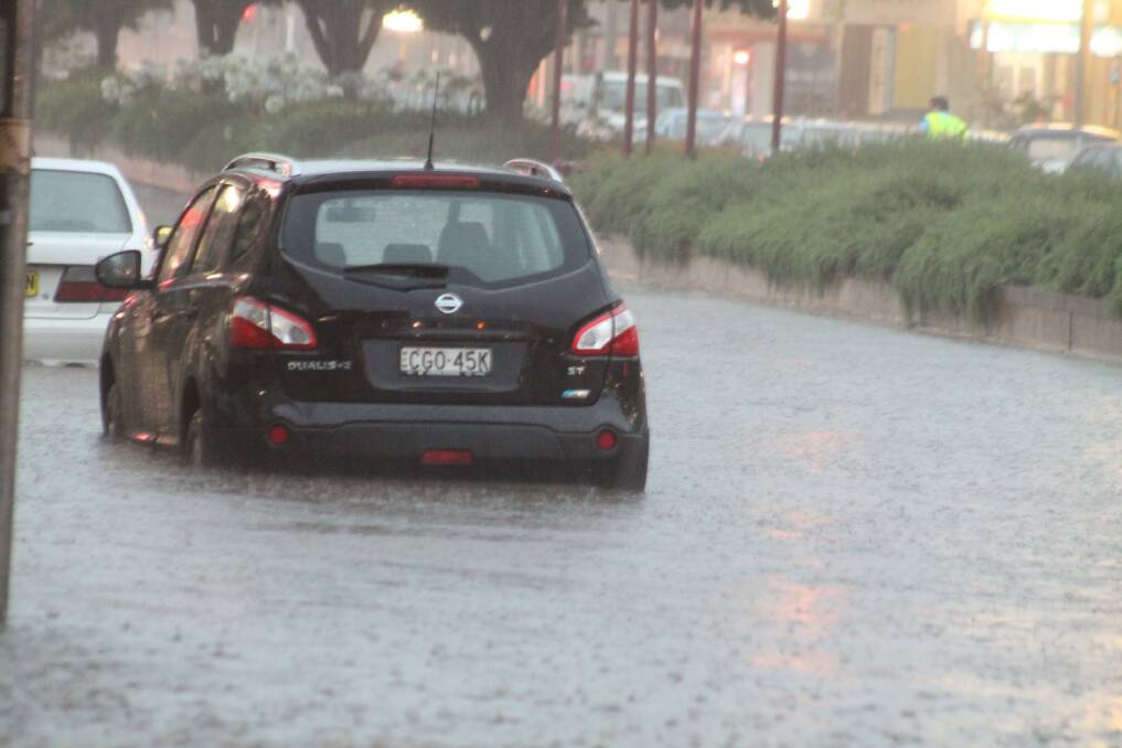 A car up to its bumper in water on Monaro Street. 
