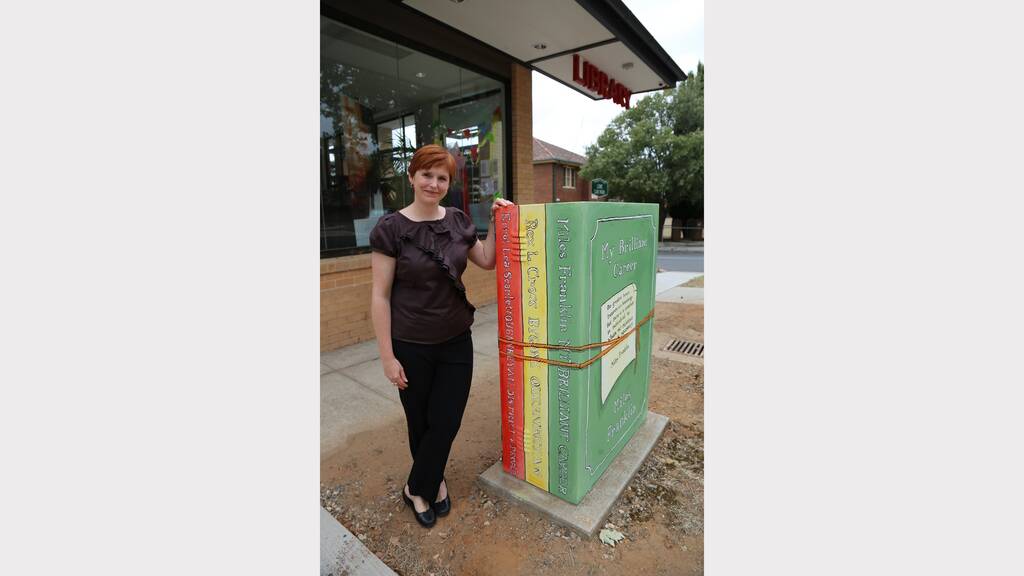 Queanbeyan City Council cultural development officer Georgina Perri with the town's newest public art addition - a powerbox disguised as a stack of books. Photo: Kim Pham.