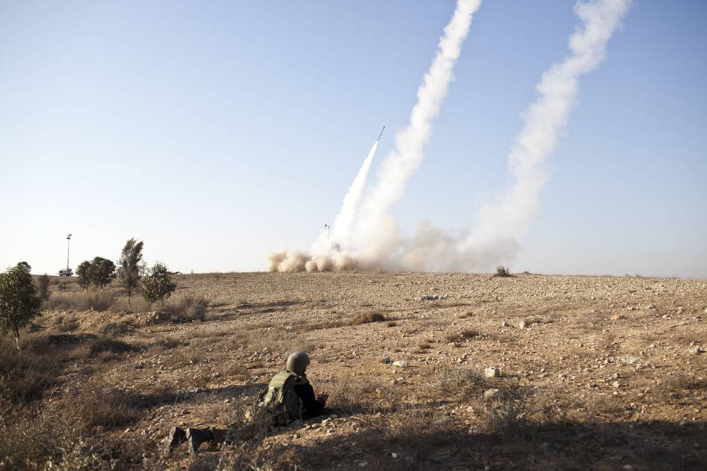 An Israeli soldier lies on the ground as missiles are fired from an Iron Dome anti-missile station near the city of Beer Sheva, Israel. Photo by Ilia Yefimovich/Getty Images