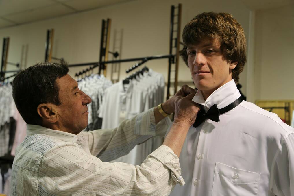 Harry Statos helps Queanbeyan High School student Norman Lembit get suited up for the year 12 formal.