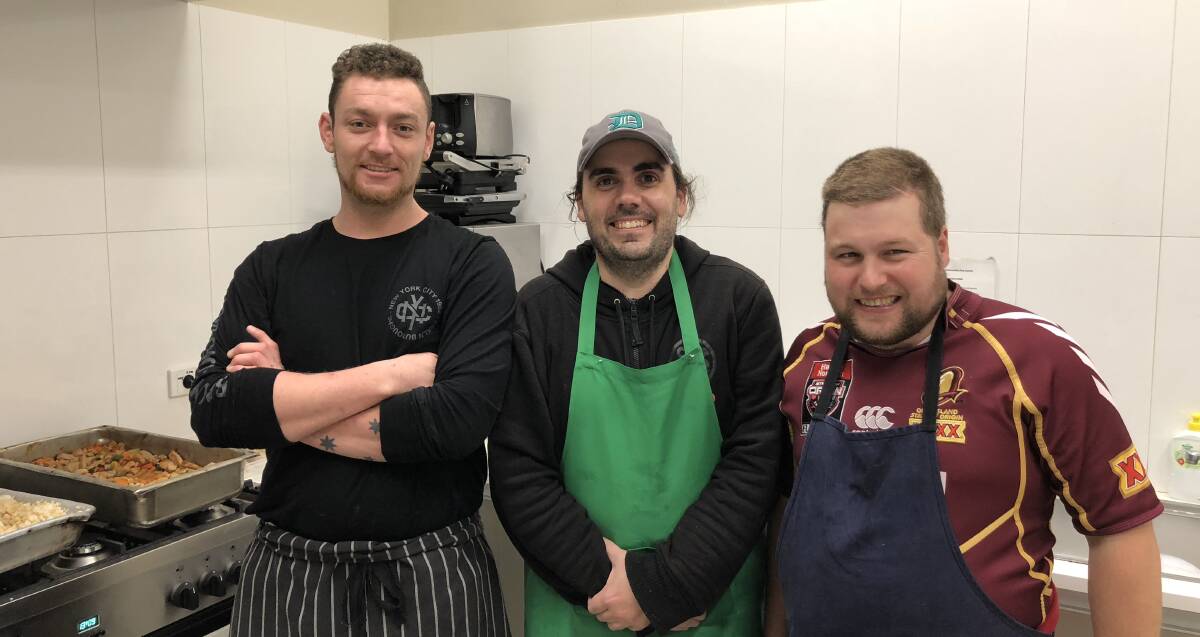Mitchell McMahon, Andrew Connelly and John volunteer their time to cook meals for clients of St Benedict's. Photo: Elliot Williams