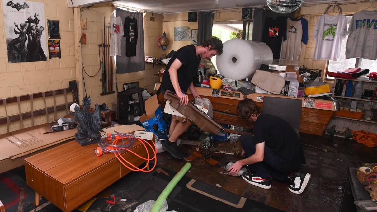 Neighbours clean a house after floodwaters receded in Oxley, in Brisbane. (Jono Searle/AAP PHOTOS)